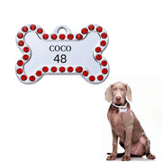 Personalized pet ID tag in bone shape with red gemstones, displaying the name 'COCO' and number '48', with a dog beside it.